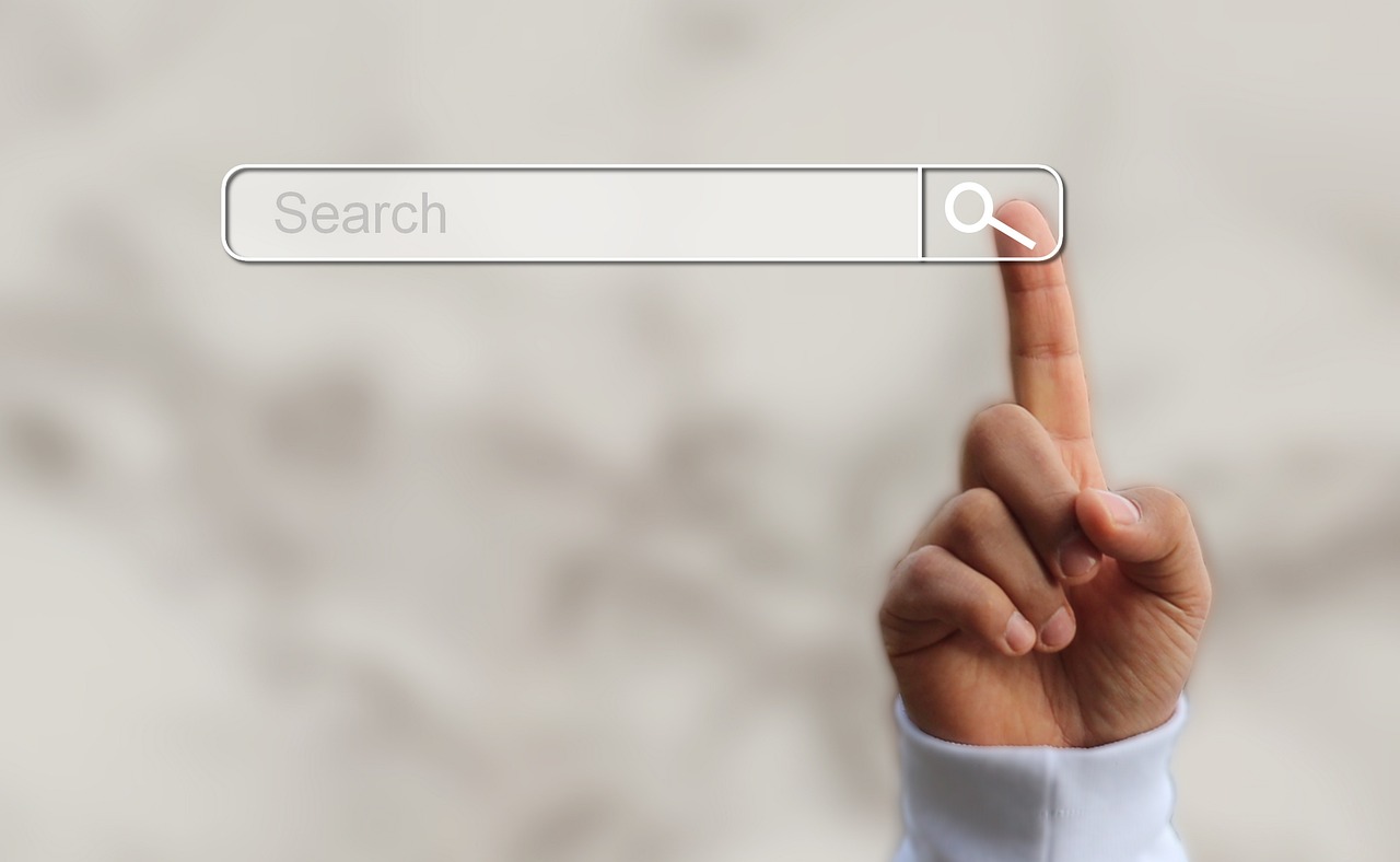 A finger pointing to the search bar magnifying glass icon